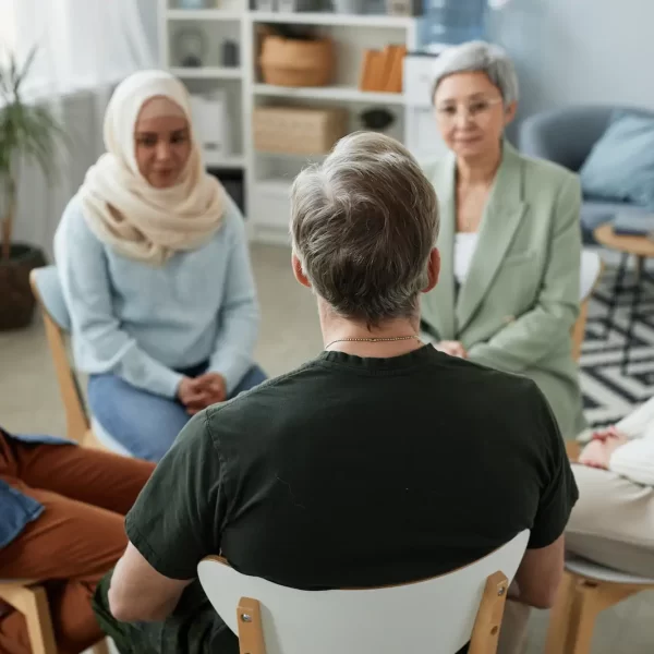 focus-rear-view-mature-male-patient-counselor-sitting-front-group